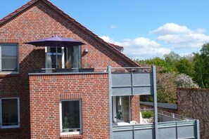 A two-story brick building with a balcony, large windows, and a stone wall. - Holiday apartment with 2 bedrooms (Ostseebad Rerik)