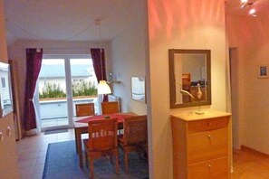A room with a dining table, chairs, a mirror, and a dresser. - Holiday apartment with 2 bedrooms (Ostseebad Rerik)