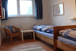 A small, cozy room with a single bed, a chair, a small table, and a radiator. - Holiday apartment with 2 bedrooms (Ostseebad Rerik)