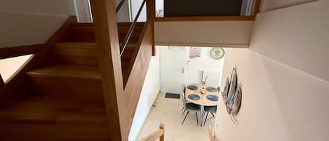 Un escalier menant à une salle à manger équipée d’une table et de chaises.