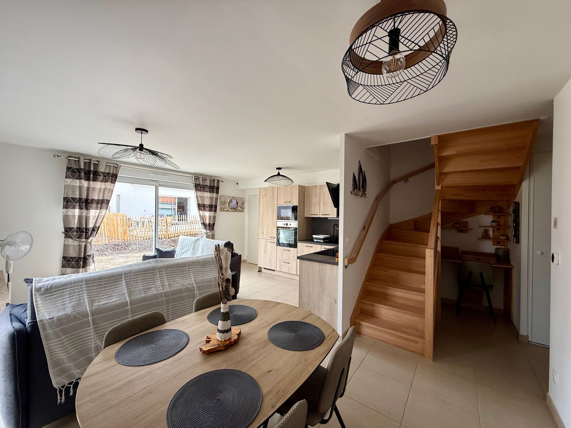 A dining area with a wooden table, black placemats, and a view of the outside.