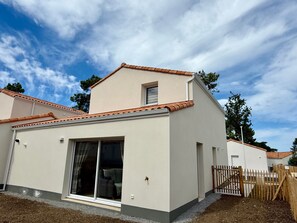 A modern two-story house with a tiled roof, large sliding glass doors, and a fenced yard. - Modern house near forest - PMR - 6 guests (Saint-Jean-de-Monts)
