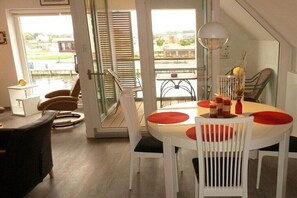 A dining area with a table and chairs, a view of a body of water, and a door leading outside. - Sharp "Utkiek" || Wismar (Wismar)