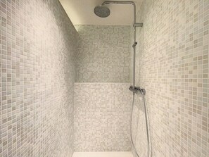 Un baño estrecho con paredes de azulejos y ducha.