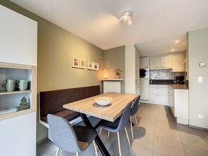 Una cocina moderna con armarios blancos, una mesa de comedor de madera y un banco.