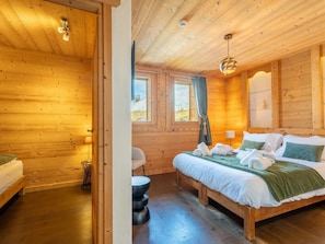 A wooden cabin room with a bed, a chair, a table, and a window. - Spacious apartment, jacuzzi, parking - 15 guests (Les Gets)