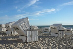 Strandliegen mit Nummern, angeordnet auf einem Sandstrand.