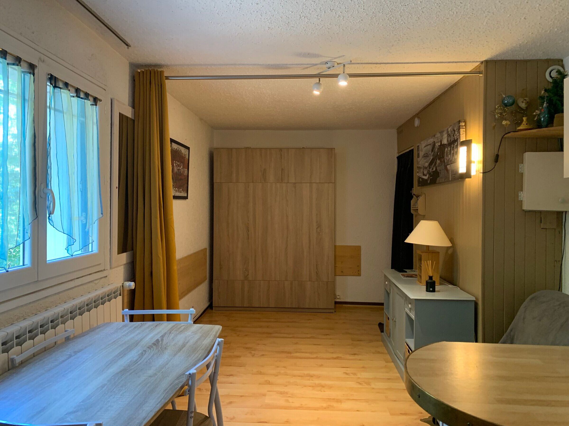 Une pièce avec un plancher en bois, une table à manger, une chaise, un buffet et une lampe.