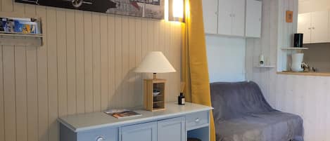 Una habitación con una cama, una mesita con una lámpara, un estante en la pared y un cuadro.