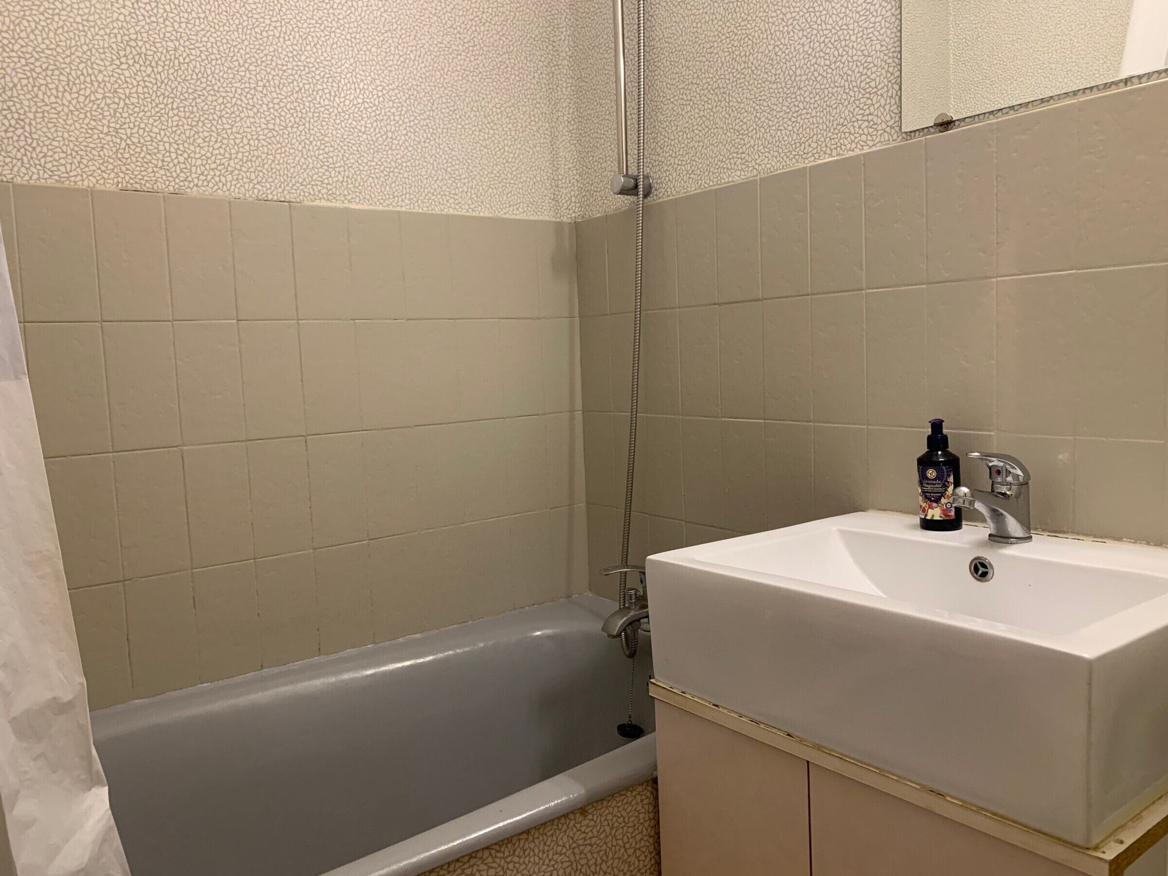 A bathroom with a bathtub, a sink, and a mirror.