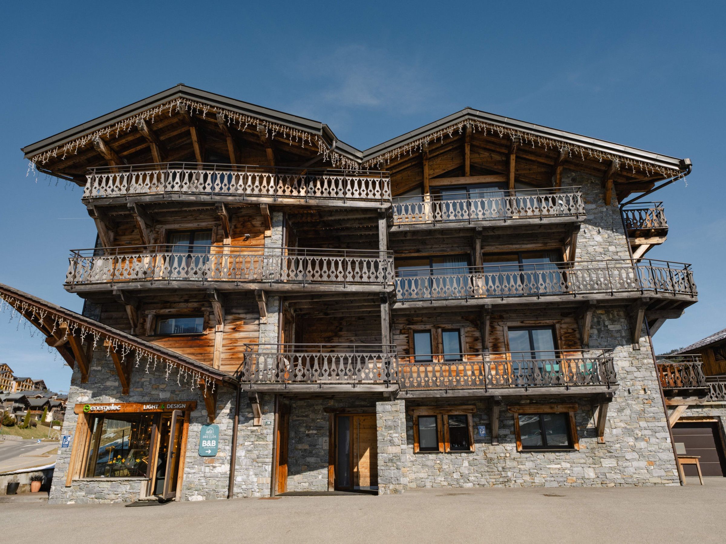 Un immeuble en bois à plusieurs étages, doté de balcons, avec une entrée bien visible au niveau du sol et une enseigne indiquant qu’il s’agit d’un Bed and Breakfast.