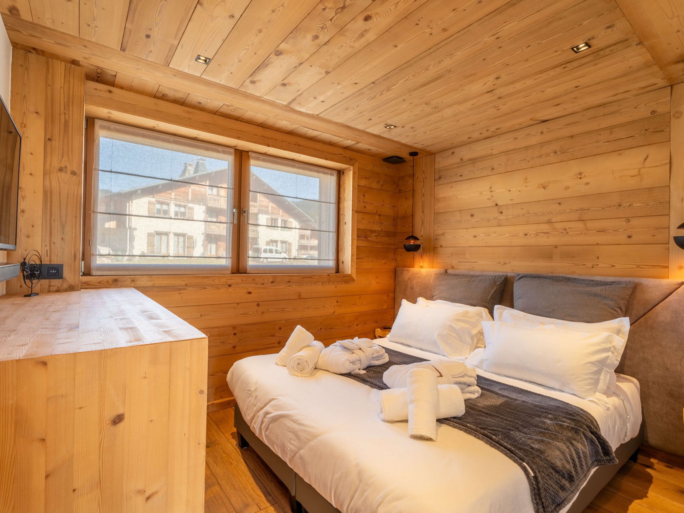 Ein Schlafzimmer einer Holzhütte mit einem Bett, Kissen und Handtüchern.