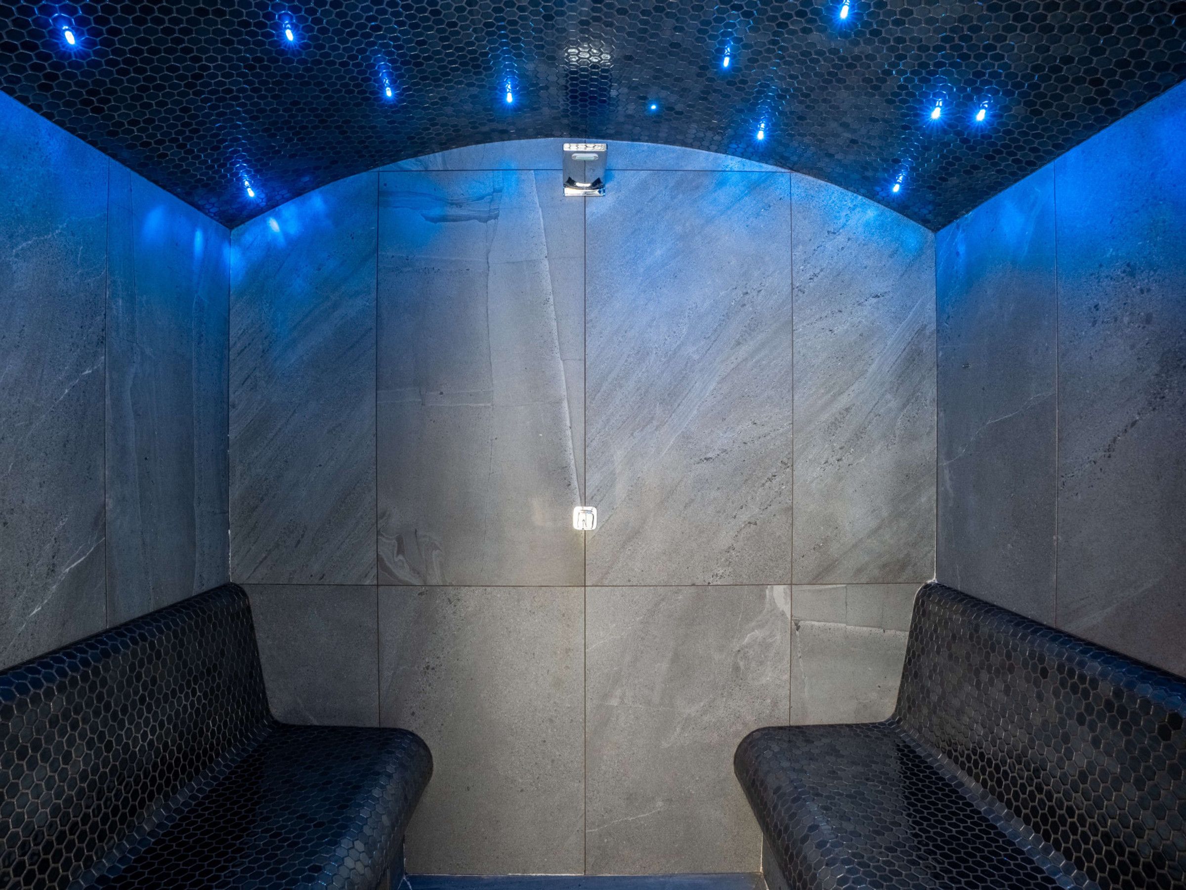Une salle de spa dotée d’un plafond hexagonal, de deux espaces détente et d’un luminaire central.