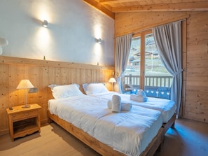 Ein Zimmer aus Holz mit einem Bett, Nachttischlampen und einem Fenster mit Vorhängen.