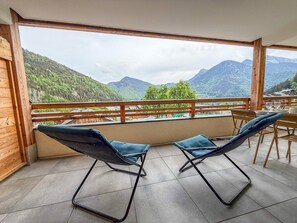 A balcony with two lounge chairs, a wooden railing, and a view of a mountainous landscape. - Spacious apartment with mountain view (Saint-Jean-d'Aulps)