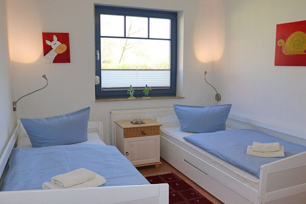 Une chambre avec deux lits simples, une fenêtre et des œuvres d’art accrochées aux murs.