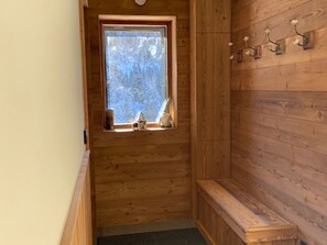 A wooden cabin with a window, a bench, and wall-mounted hooks. - Cozy apartment with parking - 4 guests (Les Gets)