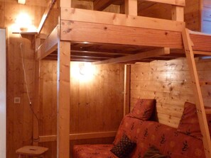 A wooden interior with a bunk bed structure, a small stool, and a wall-mounted light fixture. - Spacious chalet near slopes - 10 guests (Arêches-Beaufort)