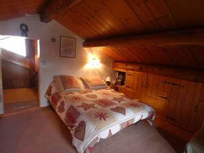 A cozy attic bedroom with a bed, a nightstand, and a wooden wardrobe. - Spacious chalet near slopes - 10 guests (Arêches-Beaufort)