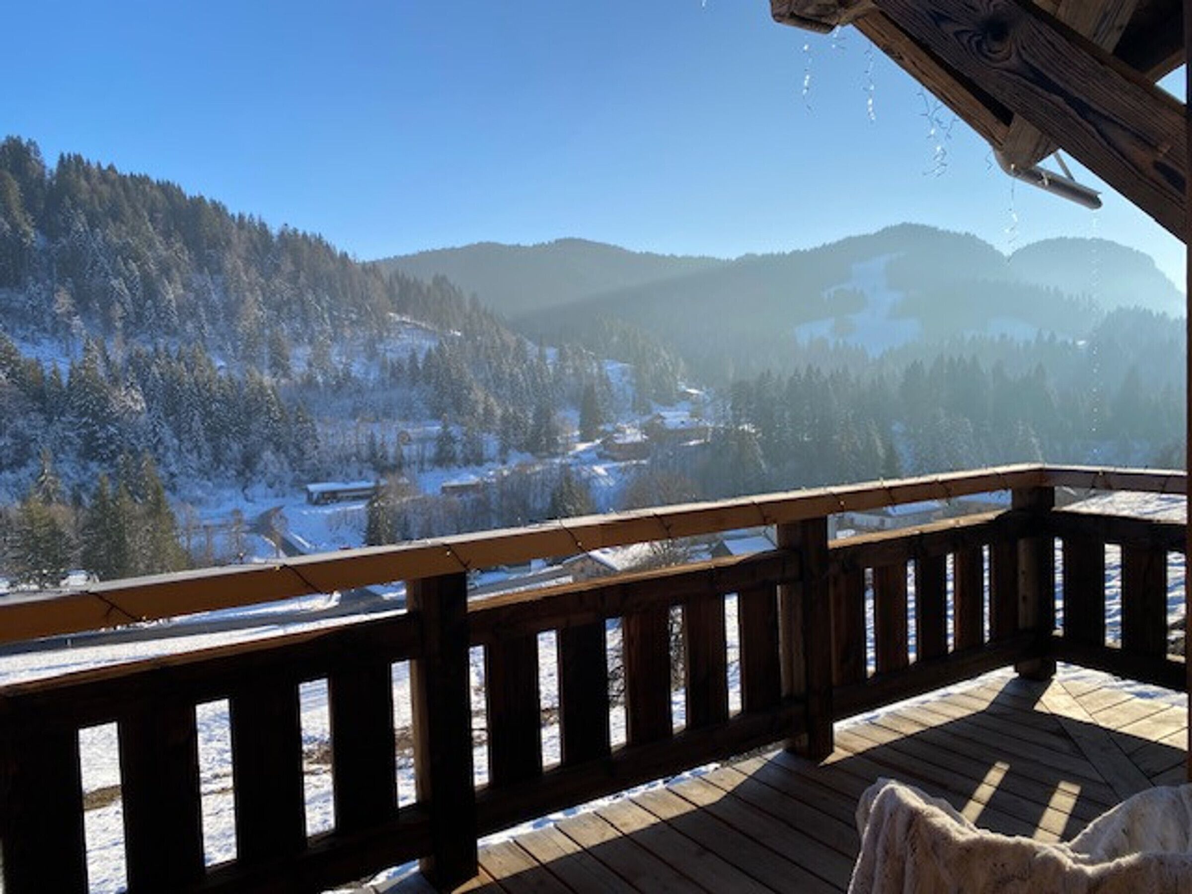 Una terraza de madera con vista a un paisaje nevado y montañas.