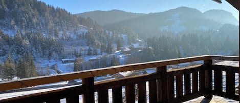 A wooden deck with a view of a snowy landscape and mountains.