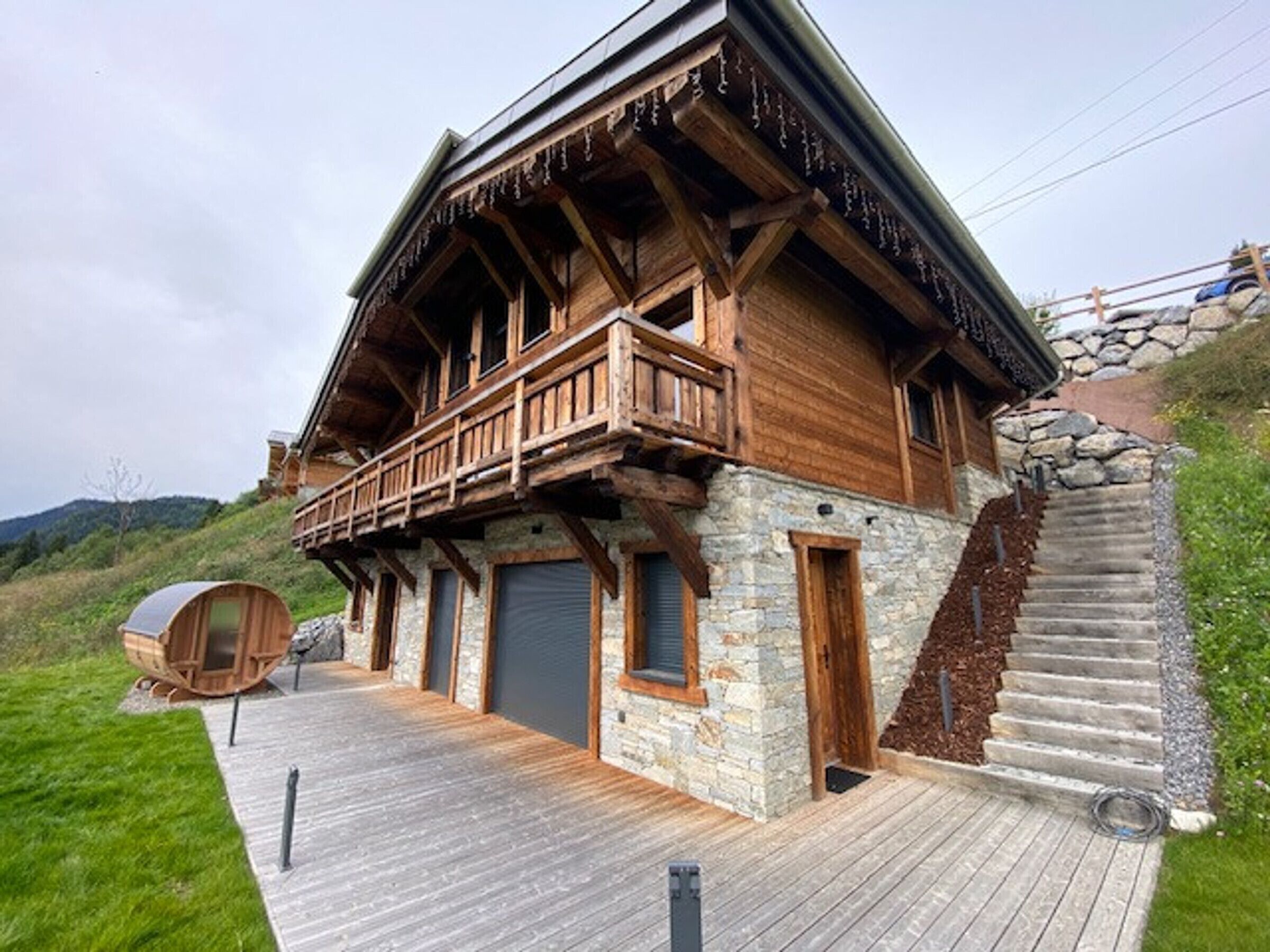 A wooden chalet with a balcony, stone walls, and a wooden deck.