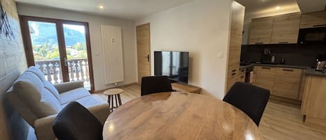 A modern living room with a sofa, a dining table, and a TV.