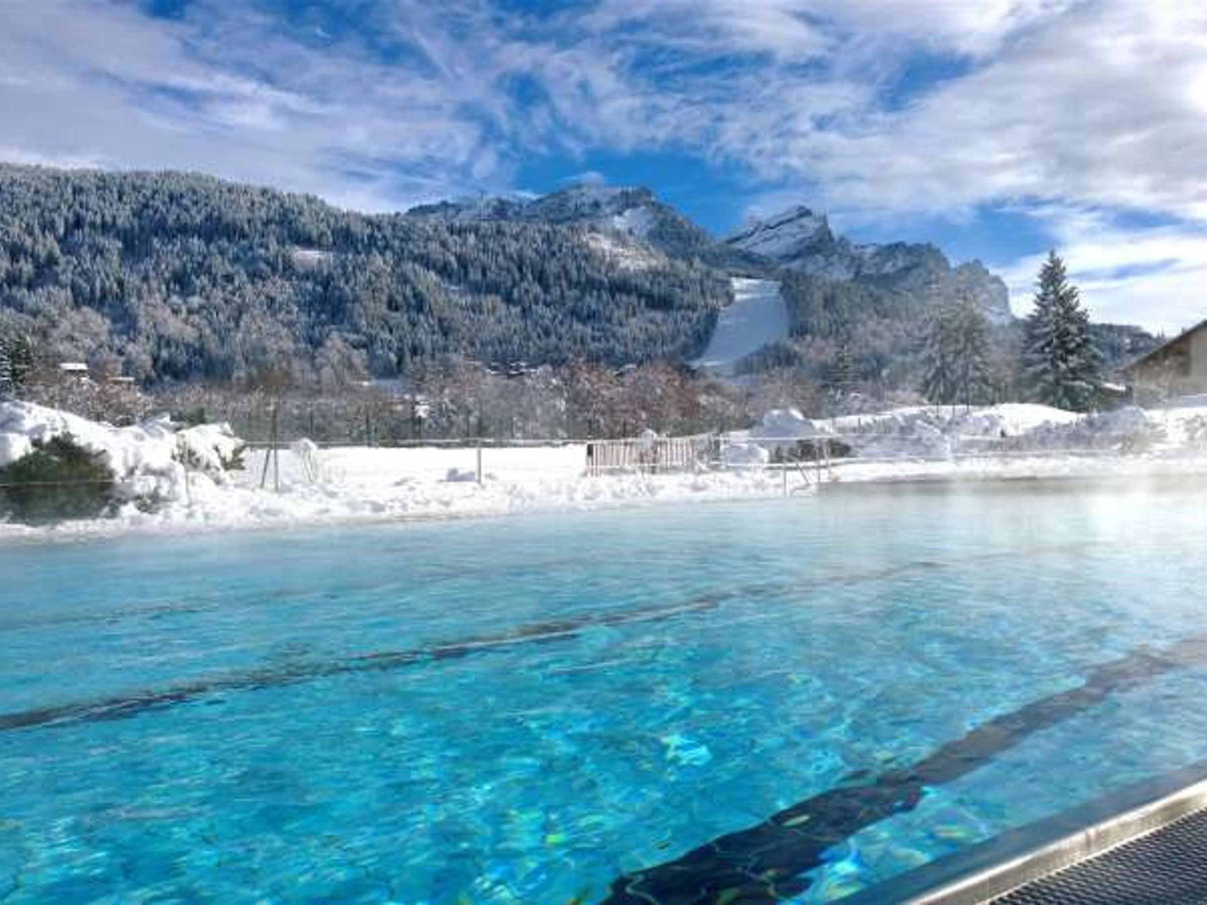A clear blue pool with a mountain backdrop.