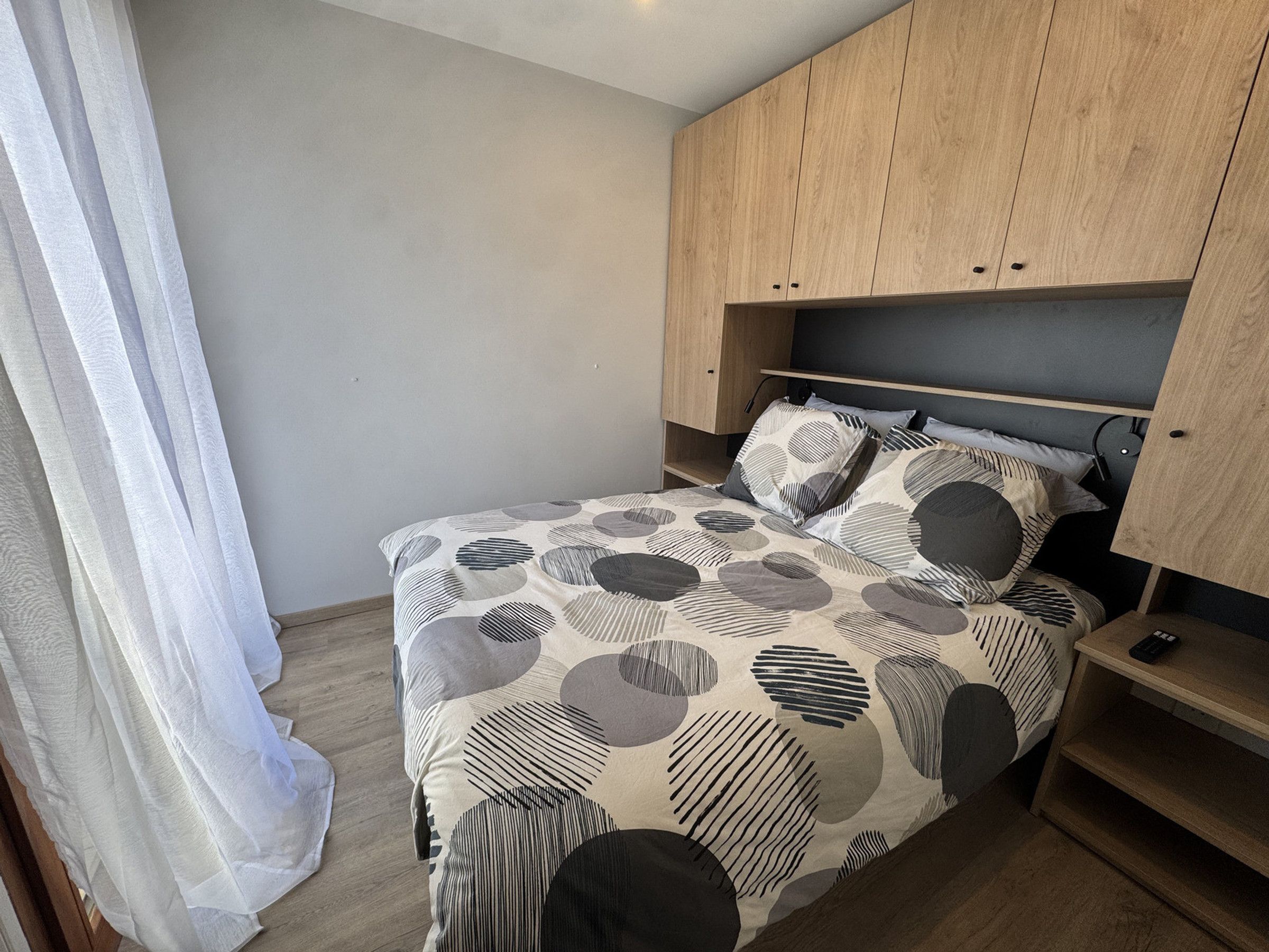 A bedroom with a bed, wooden headboard, and a nightstand.