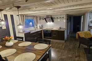 A modern kitchen with wooden cabinets, a built-in oven, and a dining area with a wooden table and chairs. - Holiday home with 3 bedrooms (Wervershoof)