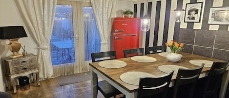 En matplats med ett träbord, svarta stolar och ett rött kylskåp.