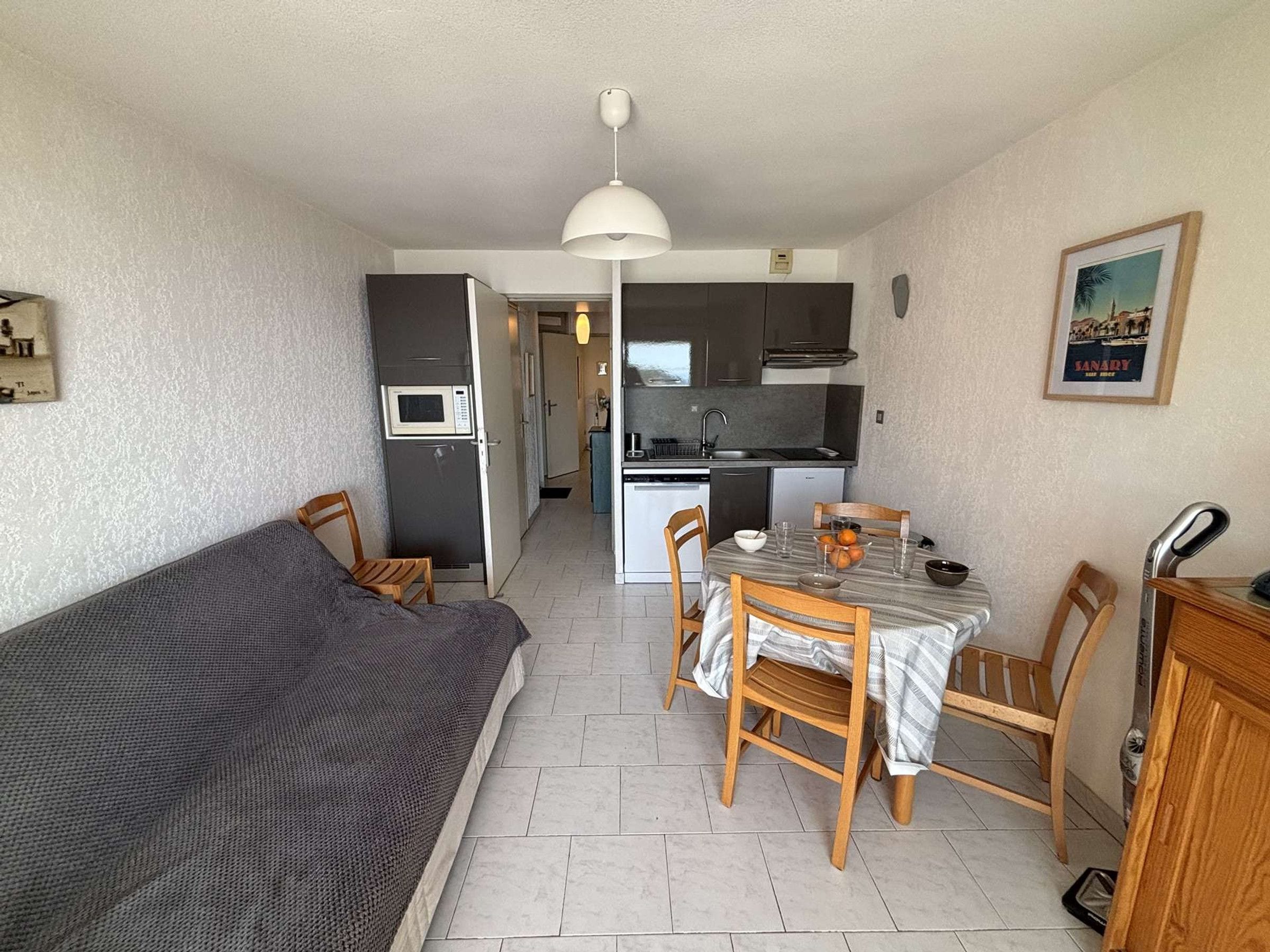 A compact living space with a kitchenette, a dining area, and a sofa.