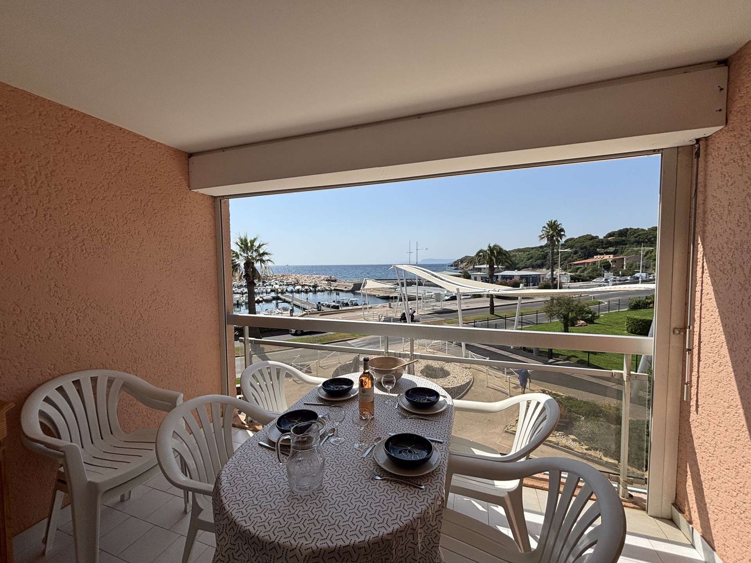 Ein Balkon mit Tisch für zwei Personen mit Blick auf einen Yachthafen und die Küste.