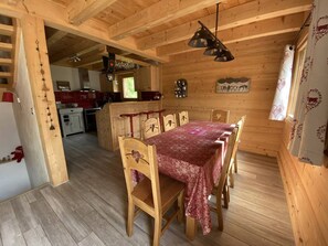 A wooden interior with a dining table set for six, a kitchen area, and a living space. - New chalet panoramic view - 8 guests (Arêches-Beaufort)