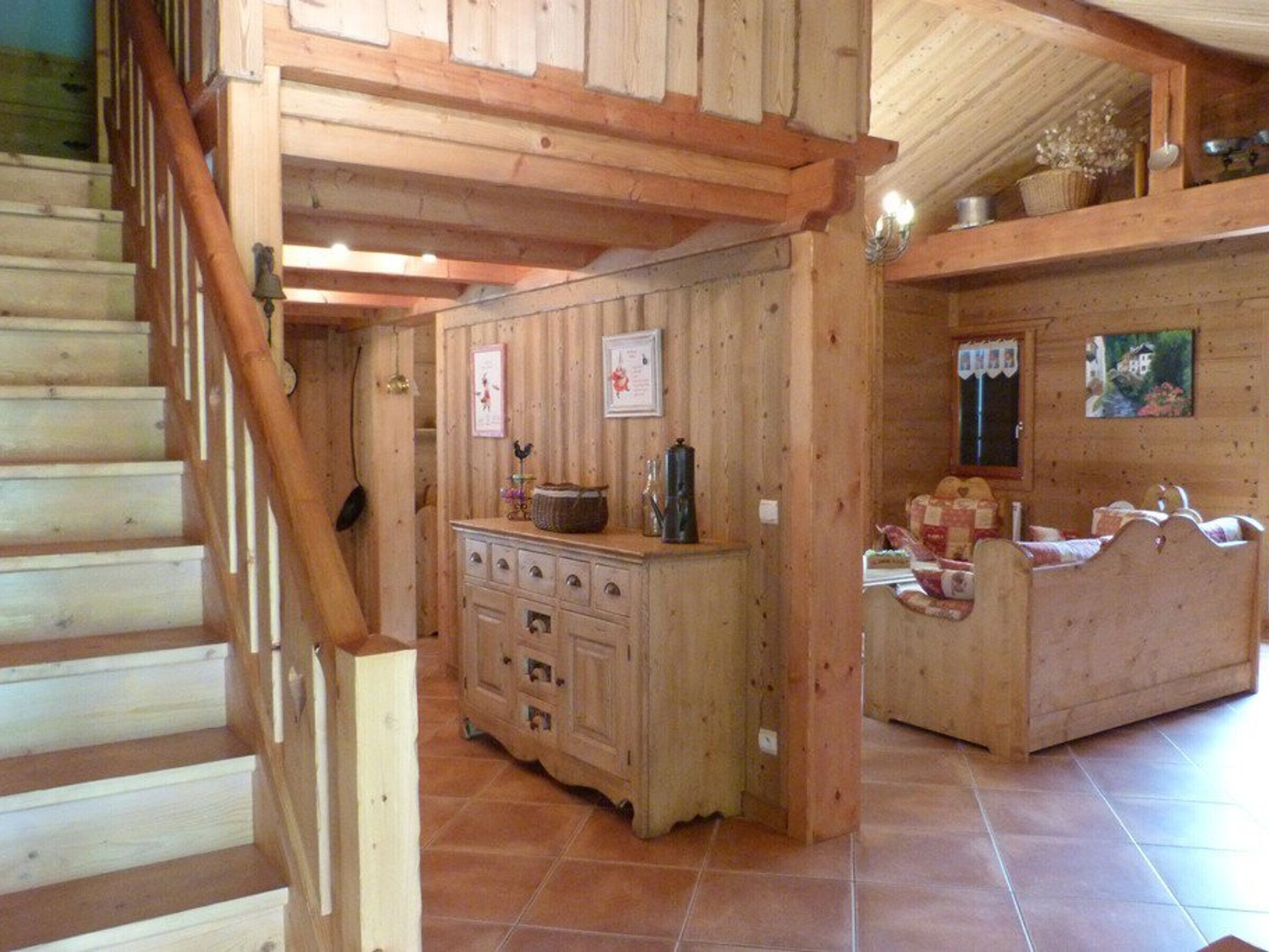 A wooden interior with a staircase, a kitchen area with cabinets, and a bed with a headboard.