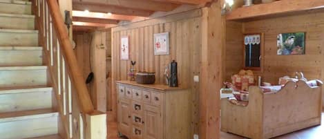 Un interior de madera con una escalera, una zona de cocina con armarios y una cama con cabecero.