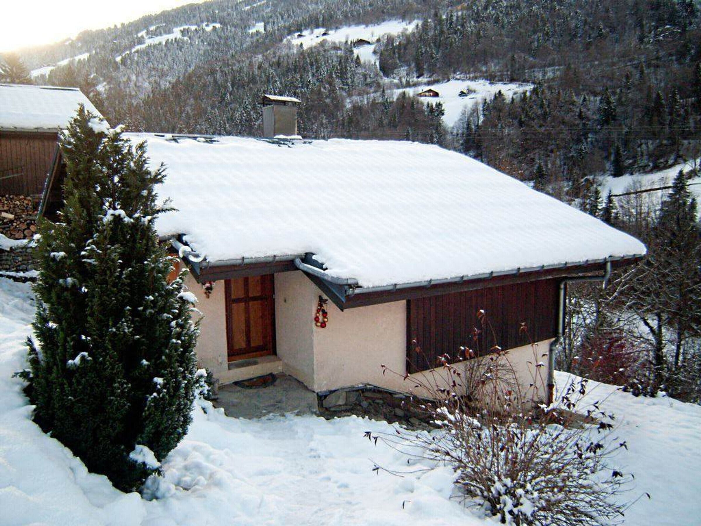A snow-covered house with a wooden door and a small porch.