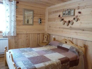 A wooden cabin bedroom with a bed, a chair, a mirror, and wall decorations. - Tastefully renovated chalet - 9 guests (Beaufort)