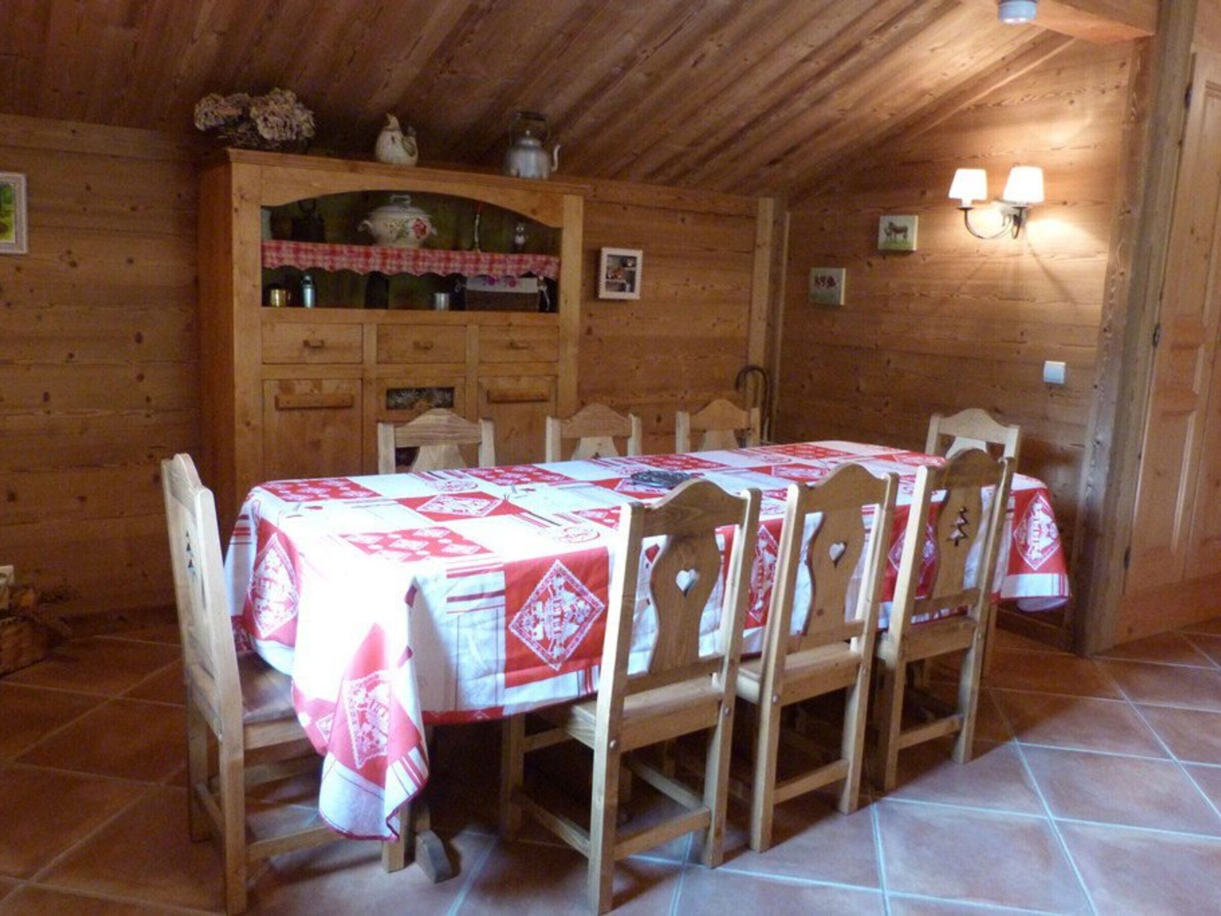 Un coin repas en bois avec une table dressée pour six personnes, entourée de chaises.