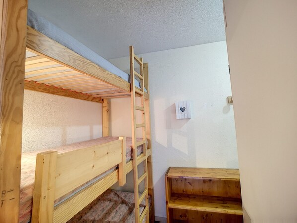 A bunk bed with a ladder, a small wooden shelf, and a wall-mounted light switch. - Cozy apartment with wifi - 6 guests, mountain view (Les Menuires)