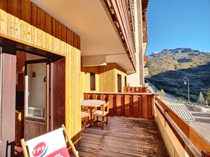 A wooden balcony with a table and chairs, overlooking a mountainous landscape. - Cozy apartment with wifi - 6 guests, mountain view (Les Menuires)