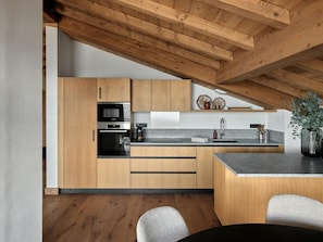 A modern kitchen with wooden cabinets, a built-in oven, and a granite countertop. - Modern penthouse in center - 8 guests (Montvalezan-La Rosière)