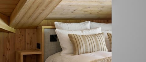 Un interior de madera con una cama, almohadas y una estantería.