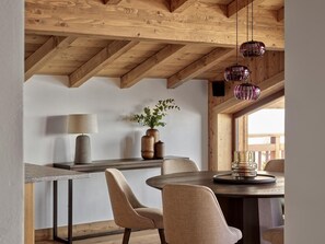 A dining area with a wooden ceiling, a table with chairs, a lamp, and a vase with plants. - Modern penthouse in center - 8 guests (Montvalezan-La Rosière)