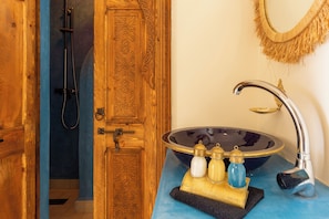 A bathroom with a wooden door, a shower, and a sink with a basin and soap dispensers. - Vrbo Property (Marrakesh)