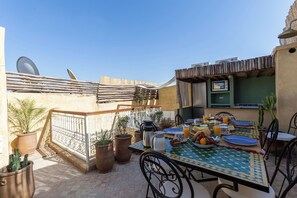 An outdoor dining area with a table set for breakfast, surrounded by potted plants and a wooden fence. - Vrbo Property (Marrakesh)