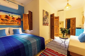 A room with a bed, a painting, a door, and a vase with flowers. - Vrbo Property (Marrakesh)