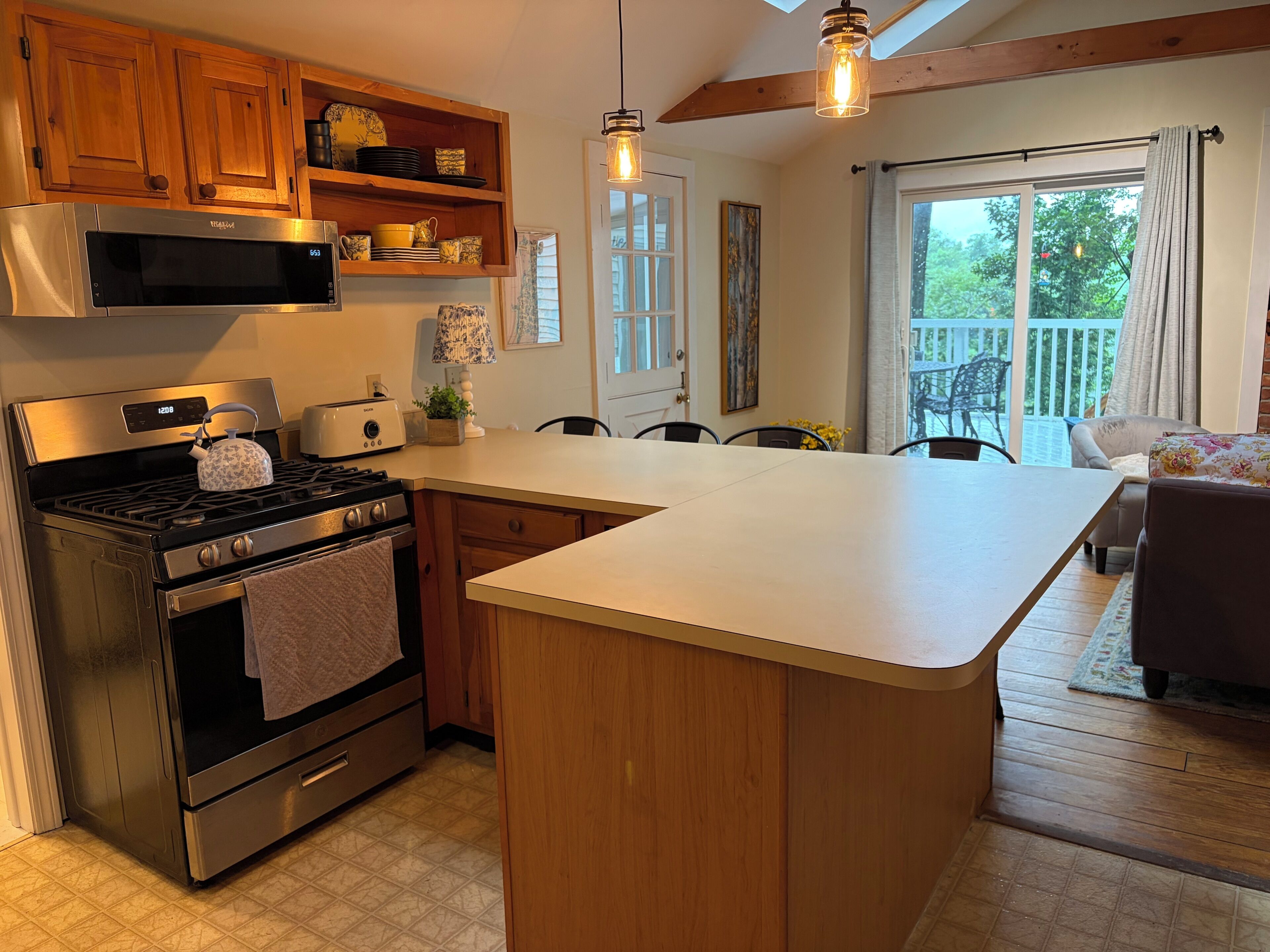 A kitchen with wooden cabinets, a microwave, a stove, and a dining area with a table and chairs.