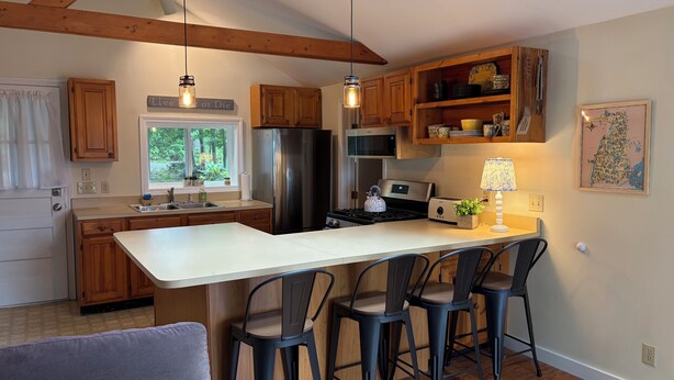 Una cocina moderna con armarios de madera, un refrigerador de acero inoxidable, horno empotrado y una isla grande con taburetes de bar.