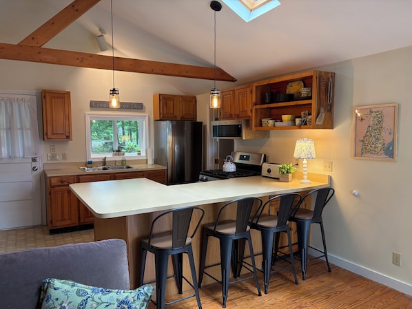 A modern kitchen with wooden cabinets, a stainless steel refrigerator, a built-in oven, and a large island with bar stools.